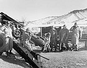 Photo:  Lieutenant Colonel Leon B. Humphrey, CO 213th Field Artillery Battalion, U.S. Eighth Army (right foreground), pulls the lanyard on north east gun of Battery A, 213th Field Artillery Battalion, to send the 100,000th round of ammunition fired by the 213th at Chinese Communist positions.