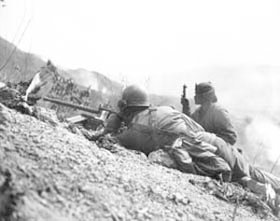 Photo:  Pfc. Jack Lee of Wichita, Kan. (left), and Cpl. Joseph W. Thomas of Honolulu, T.H., fire their machine gun.