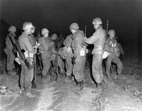 Photo:  Men of the 3rd Ranger Company, 3rd Infantry Division, adjust their gear before undertaking a dawn patrol.