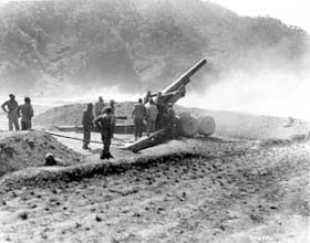 Photo:  Dust and smoke rise after a 8-inch howitzer of the 96th Field Artillery Battalion, X Corps, let loose with a 200-lb projectile.