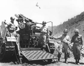 Photo:  Lt. Gen. William M. Hoge, Commanding General, U.S. IX Corps, left, holds the lanyard which will fire the 75,000th shell to be fired by the corps since the start of the conflict in Korea.