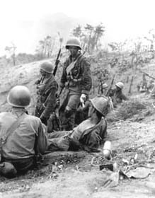 Photo:  Hit in the back during a grenade duel, Corporal Dominick F. Zegarelli, (Utica, N.Y.) Company L, 7th Regimental Combat 	  Team, U.S. 3rd Infantry Division, waits for evacuation, while other members of his platoon rest.  