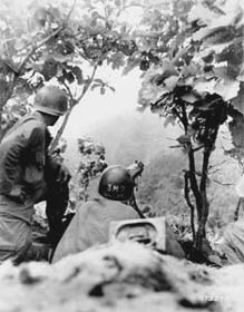 Photo:  Company "M", 7th RCT, U.S. 3rd Infantry Division machine gunners, watch for the movements of Communists forces, as artillery lands on Hill 717, one of the objectives of "Operation Doughnut".