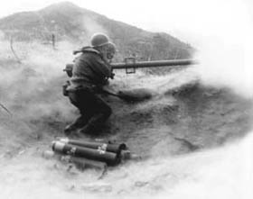 Photo:  Powder smoke and dust billow as a recoilless rifle team of Co. D, 7th infantry Regiment, 3rd U.S. Infantry Division, fire their weapon at Chinese Communist  positition on Hill 200 near Qnmong-Myon, Korea.