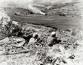 Pfc. Robert Smith of Springfield, Colo., (left) and Pvt. Carl Fisher of Ponca, Okla., 27th Infantry Regiment, dug in and firing at Communist-led North Korean positions.